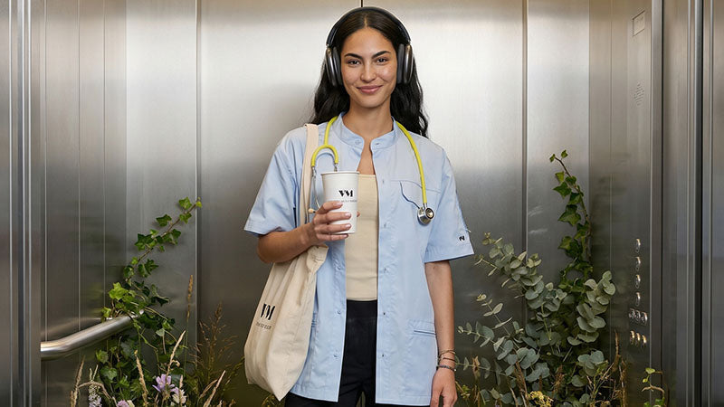 Jeune médecin portant son sac son et son stetoscope autour du cou, elle est dans un assenceur végétal qui renvoie à une image serine et fraiche