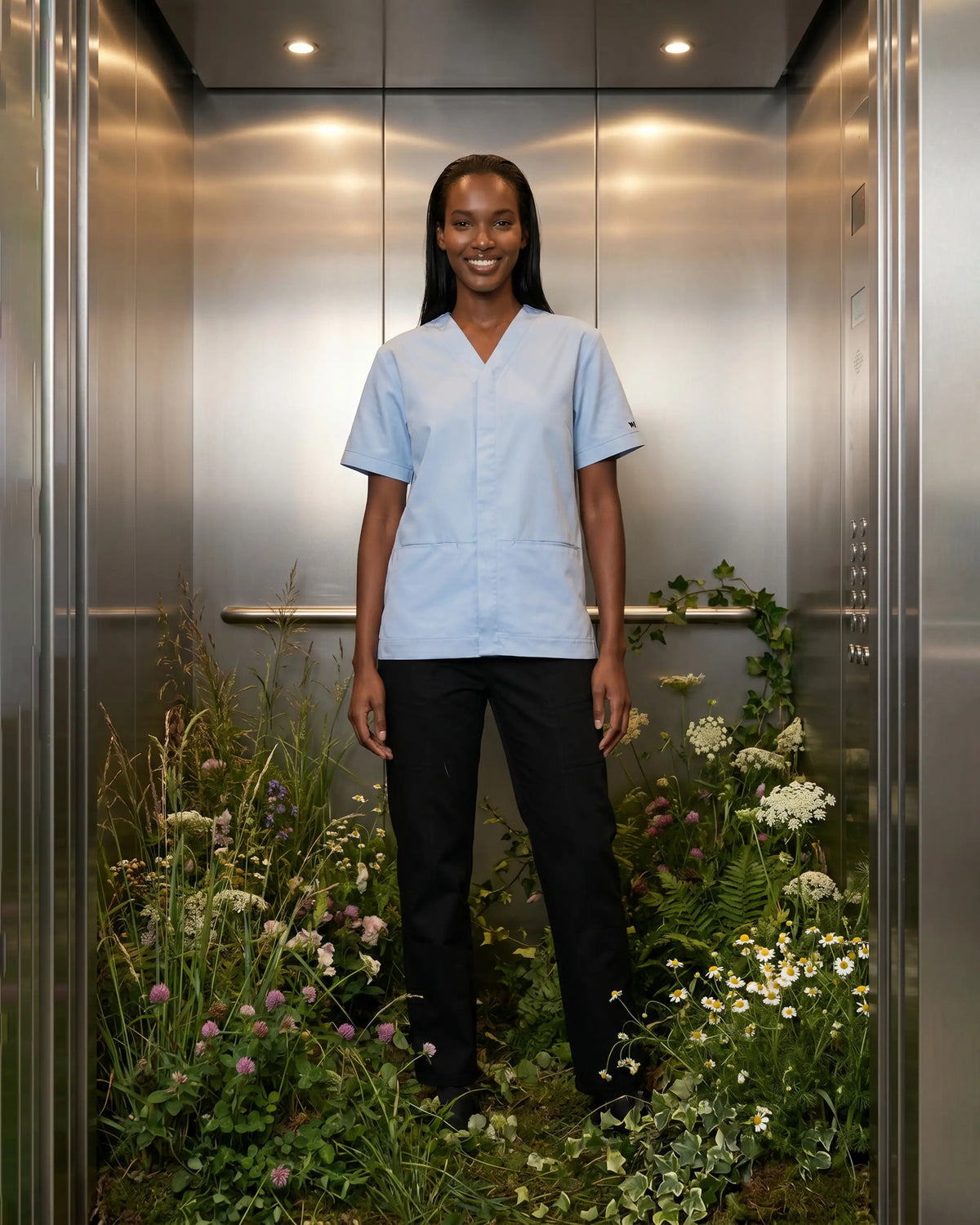 Tunique médicale Orchis bleu ciel col V, portée sur pantalon noir, coton bio - Le Vêtement Médical