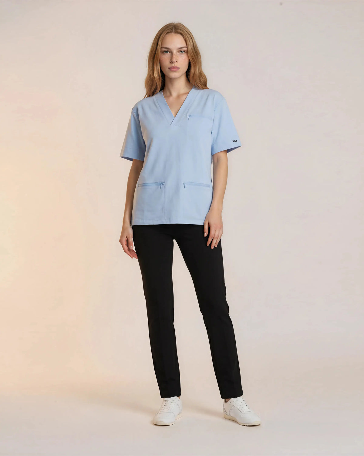 Tunique médicale Sanare bleu ciel col V, portée sur pantalon noir, en pied - Le Vêtement Médical